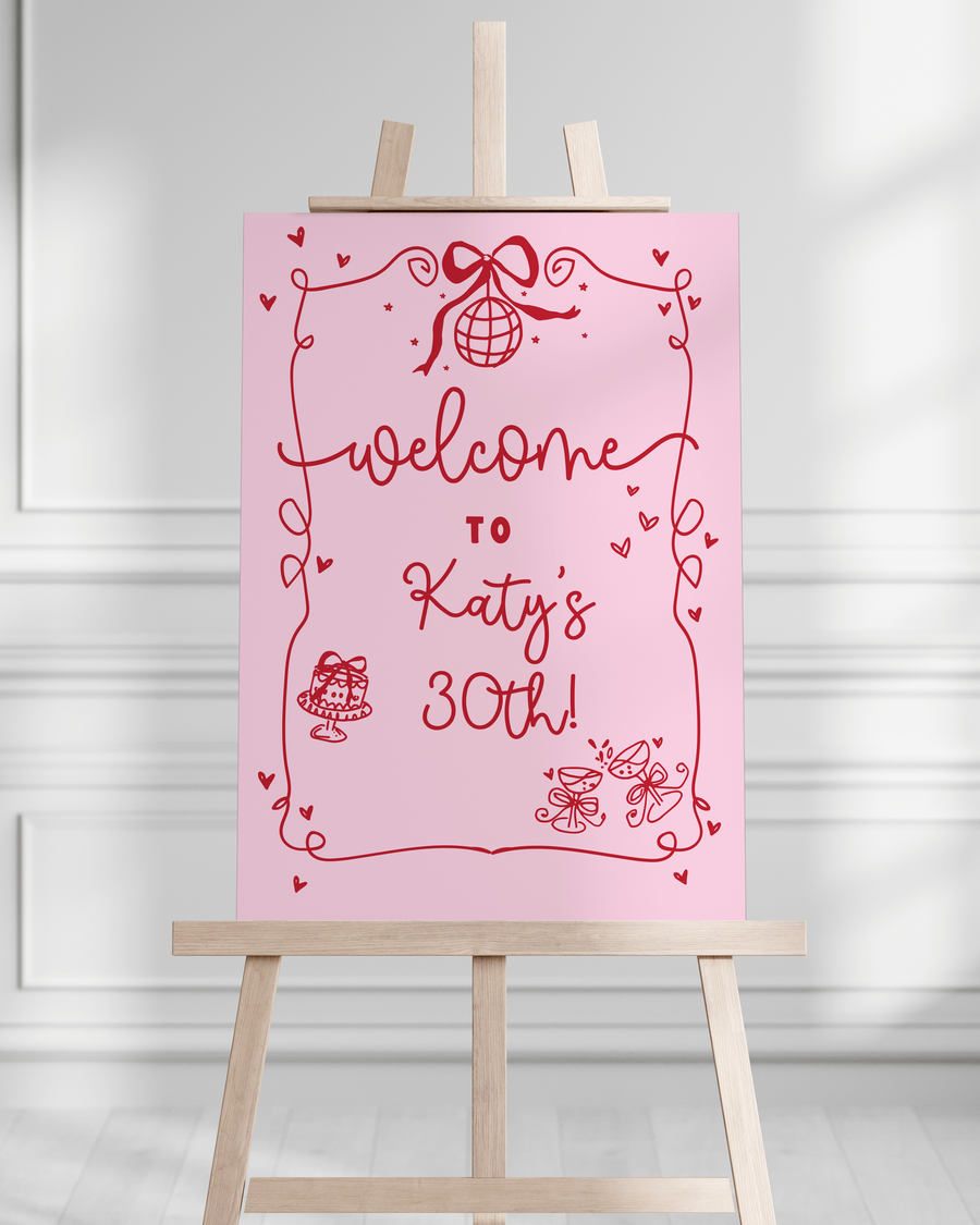 Pink birthday sign on a wooden easel against a white wall